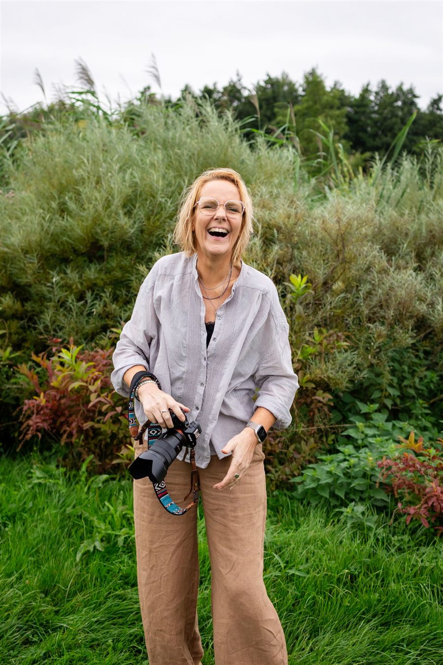 Daniëlle lacht hardop met haar camera in de hand, buiten tussen het groen